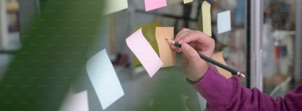 Side view of businesswoman analysing on business strategy with sticky note to remind on glass wall