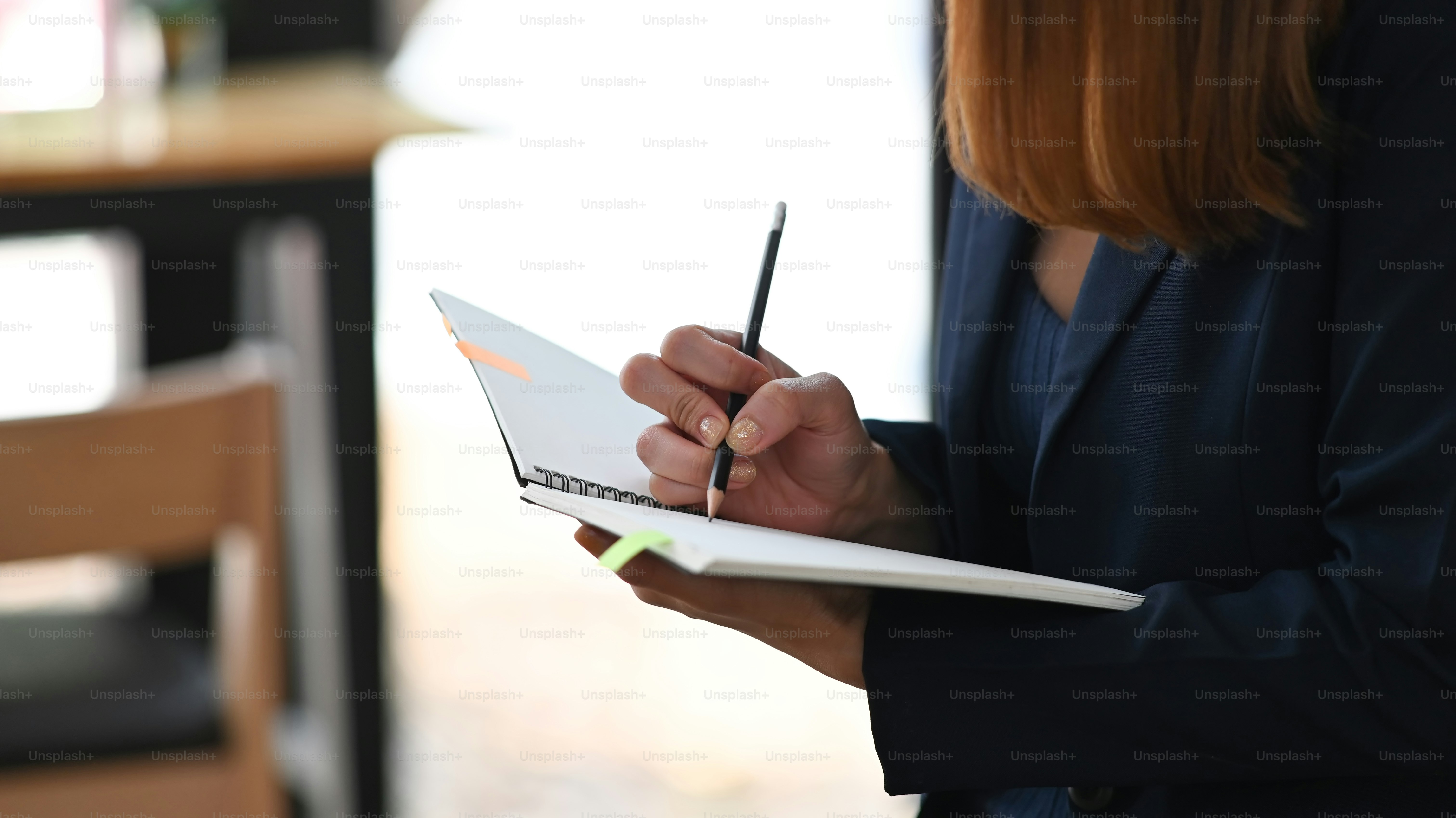 Cropped image of beautiful woman working as secretary taking note while sitting in comfortable cafe as background. Comfortable workplace concept.