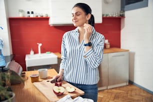Smiling lady having snack in kitchen stock photo. Lifestyle concept