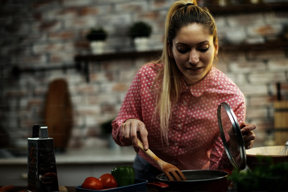Beautiful woman preparing food in kitchen. Young girl having fun while cooking at home.
