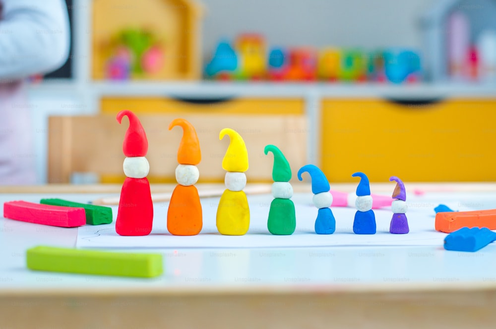 Linha de sete gnomos coloridos de argila infantil na mesa na sala das crianças. Atividades em casa para a família.