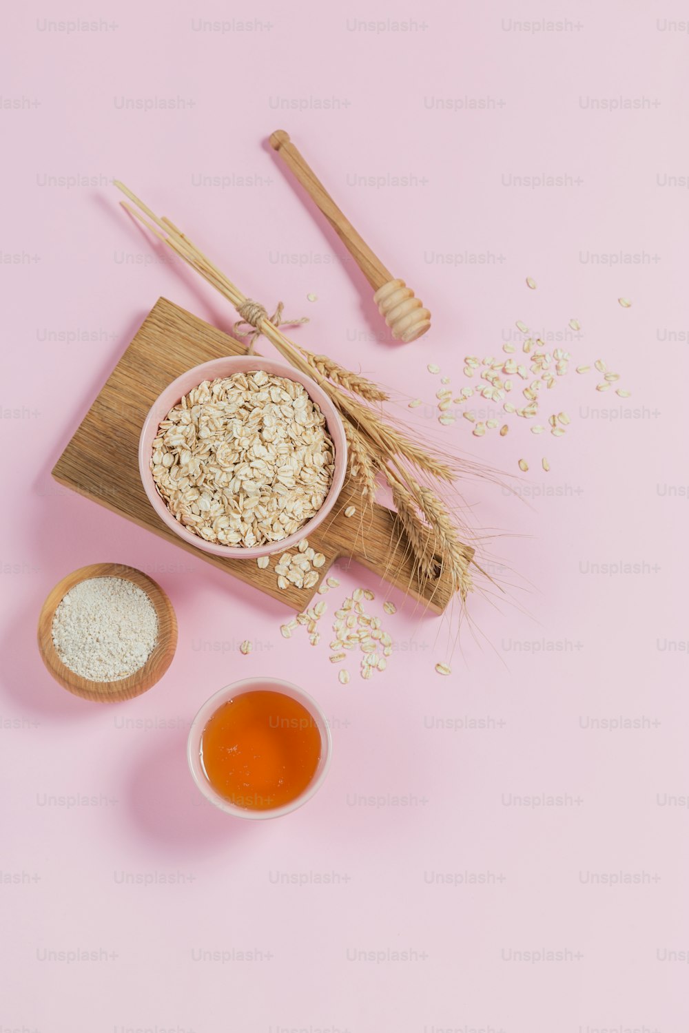 Bowl of dry oat flakes with honey, oatmeal and ears of wheat on light background. Healthy skin, facial and body care. SPA and sauna concept. Flat lay