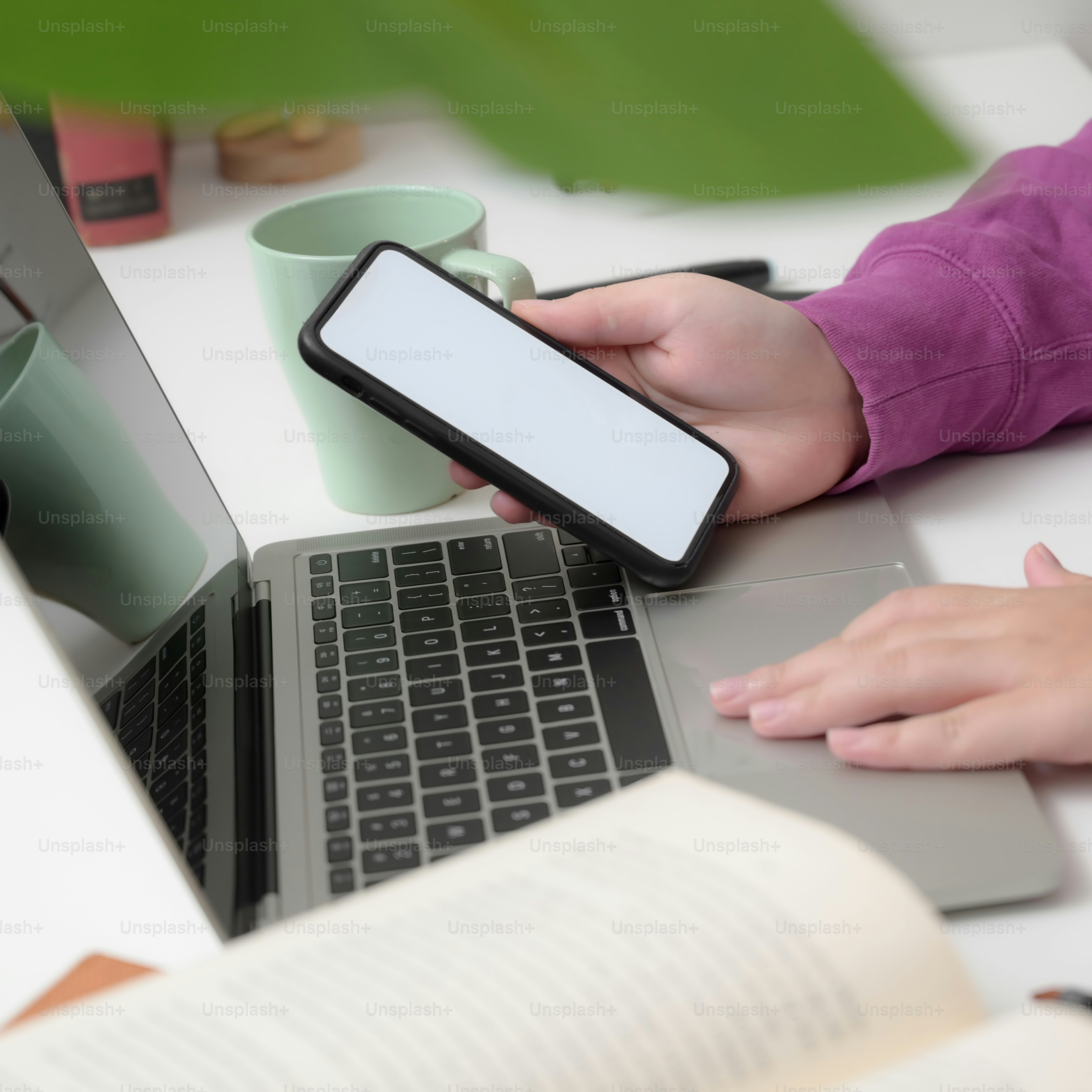Tampilan close-up gadis kolase muda yang mengerjakan proyeknya dengan komputer laptop sambil menggunakan ponsel cerdasnya