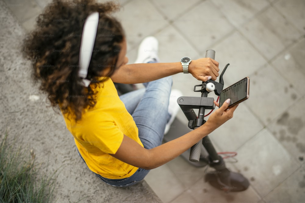 Beautiful african girl using phone on electric scooter.