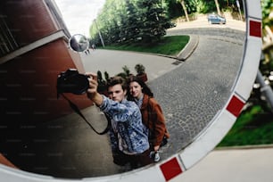 couple de hipsters heureux et élégant s’amusant à rire et à prendre des selfies dans le parc en ville au printemps ensoleillé