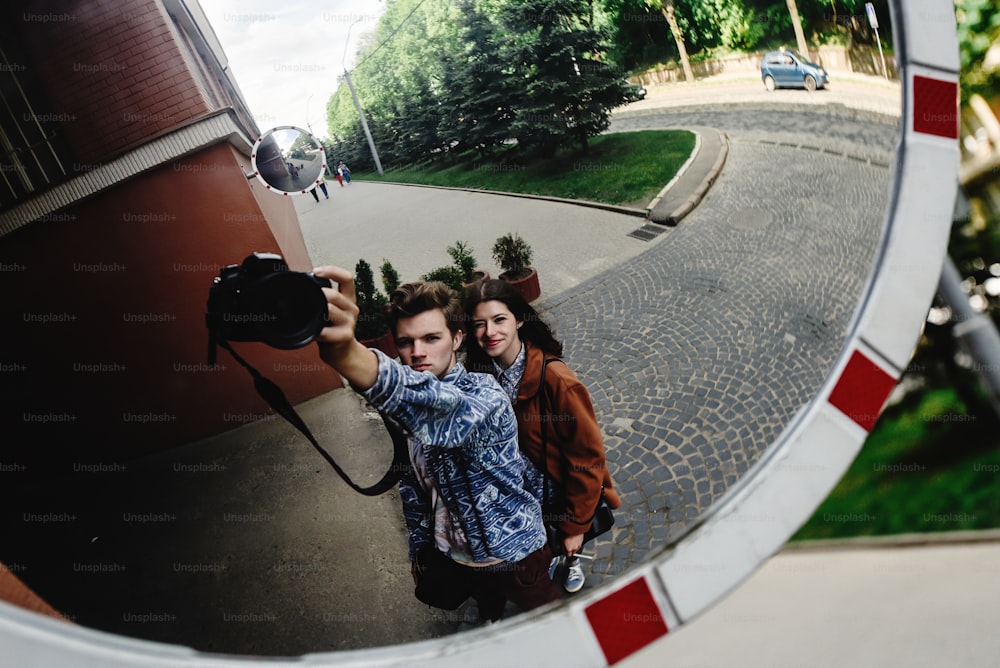 casal hipster feliz e elegante se divertindo rindo e tirando selfies no parque da cidade na ensolarada primavera