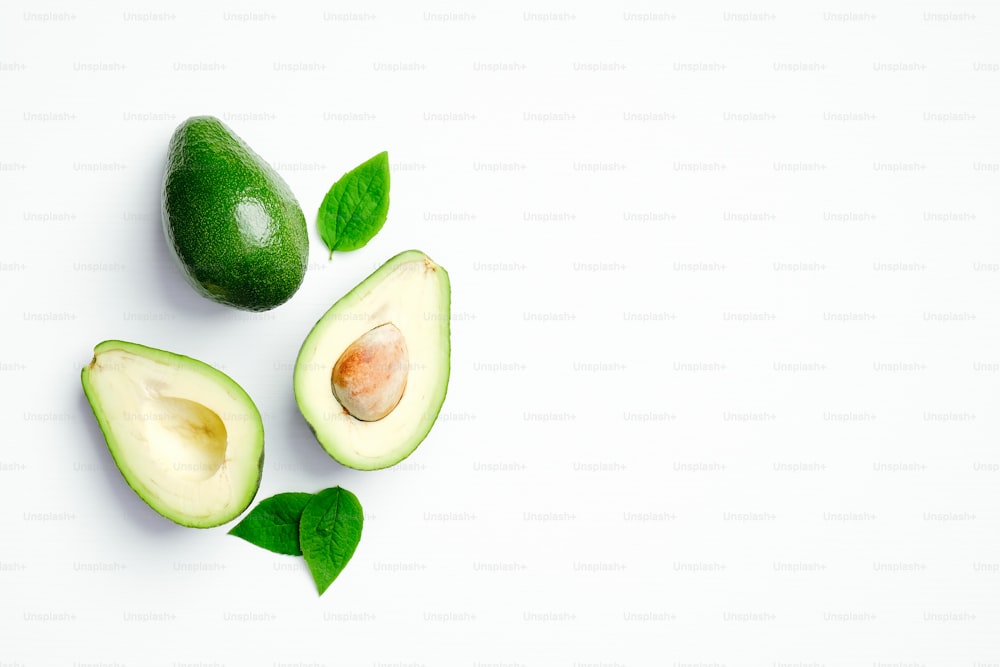 Avocado with green leaves on white background. Flat lay, top view, copy space.
