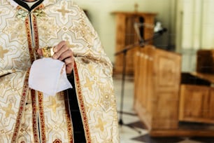 prêtre tenant un calice pour la communion, cérémonie de mariage d’une mariée blonde élégante et heureuse et d’un marié élégant dans l’église