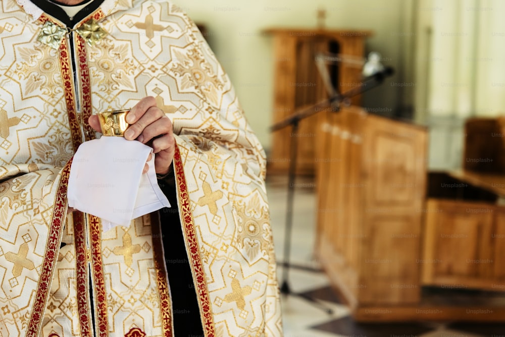 prêtre tenant un calice pour la communion, cérémonie de mariage d’une mariée blonde élégante et heureuse et d’un marié élégant dans l’église