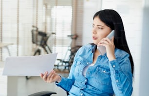 Mujer asiática irritada en la oficina hablando por teléfono