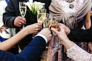 hands of happy people toasting and cheering with glasses of champagne, celebrating wedding, luxury life concept