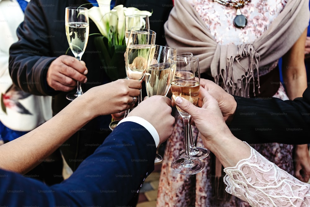 シャンパンのグラスで乾杯し、歓声を上げ、結婚式を祝う幸せな人々の手、贅沢な生活のコンセプト