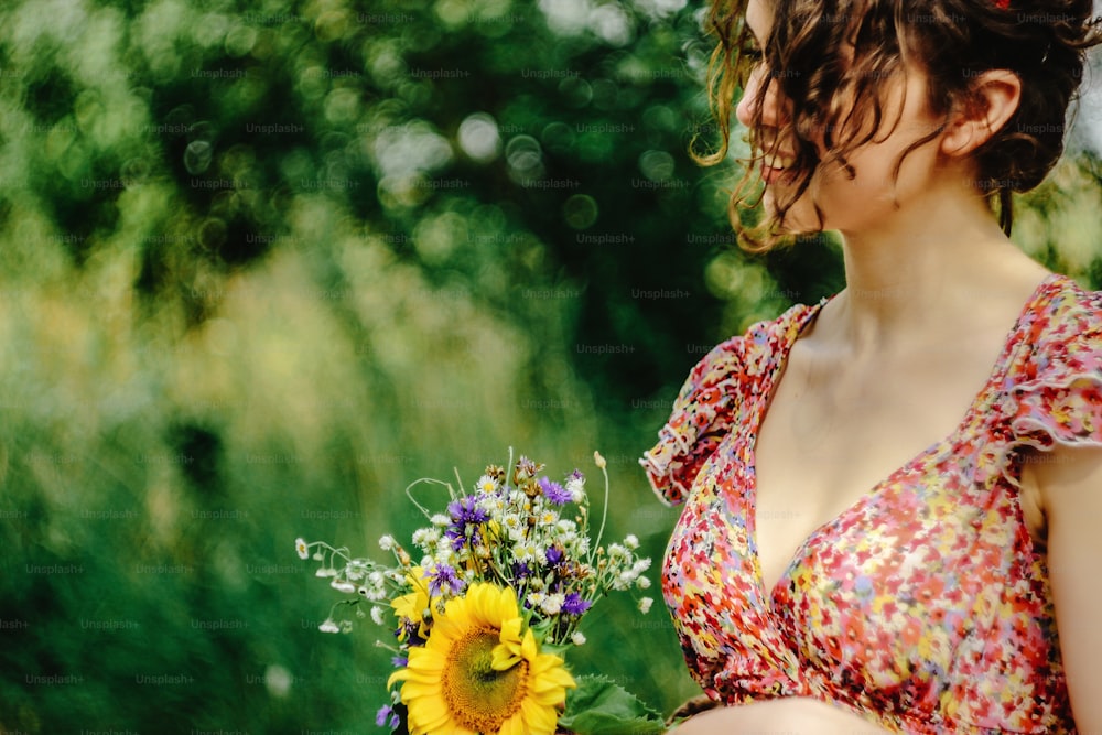 stylish gorgeous rustic bride with sunflower bouquet in colorful dress in sunny windy field