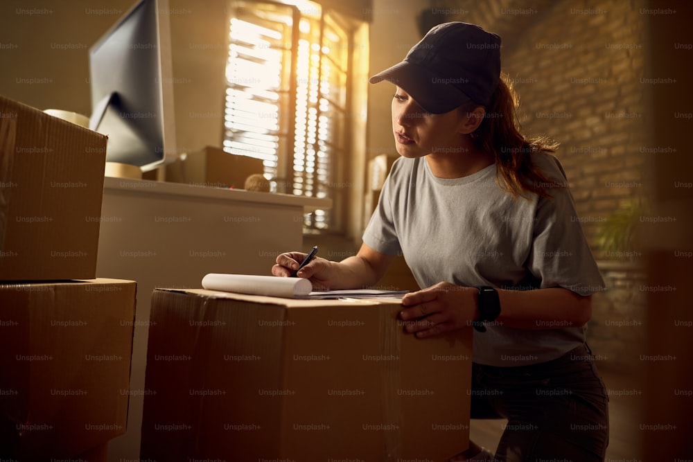 Female courier going through  a list while preparing packages for delivery in the office.