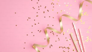 Golden party decor on pink background. Flat lay composition with confetti stars, holiday decorations and party streamer. Christmas, birthday or wedding concept. Flat lay, top view.