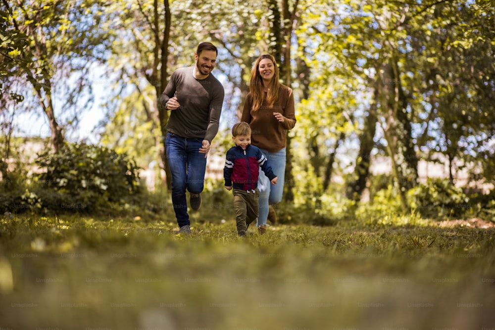 Run and catch the fun. Parents spending time with their son outside.