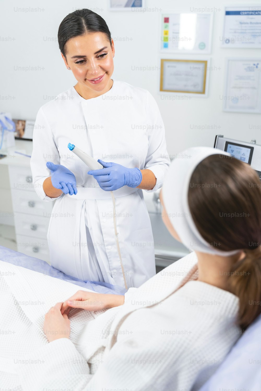 Donna in accappatoio bianco che ascolta le spiegazioni dei suoi cosmetologi prima di una procedura cosmetica
