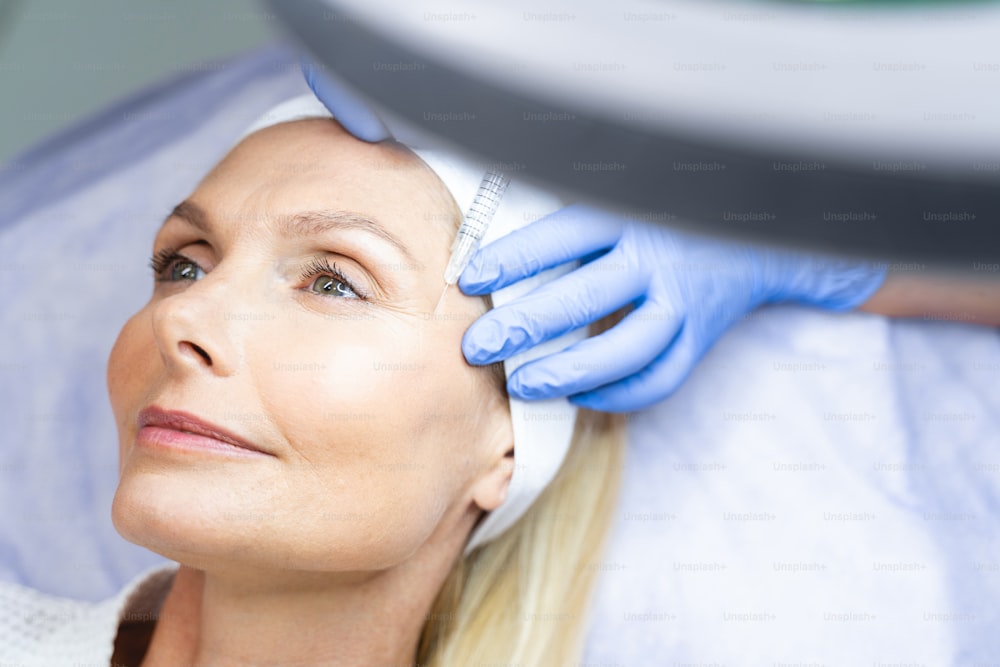 Close up portrait of an attractive blonde woman with a dreamy look getting injection