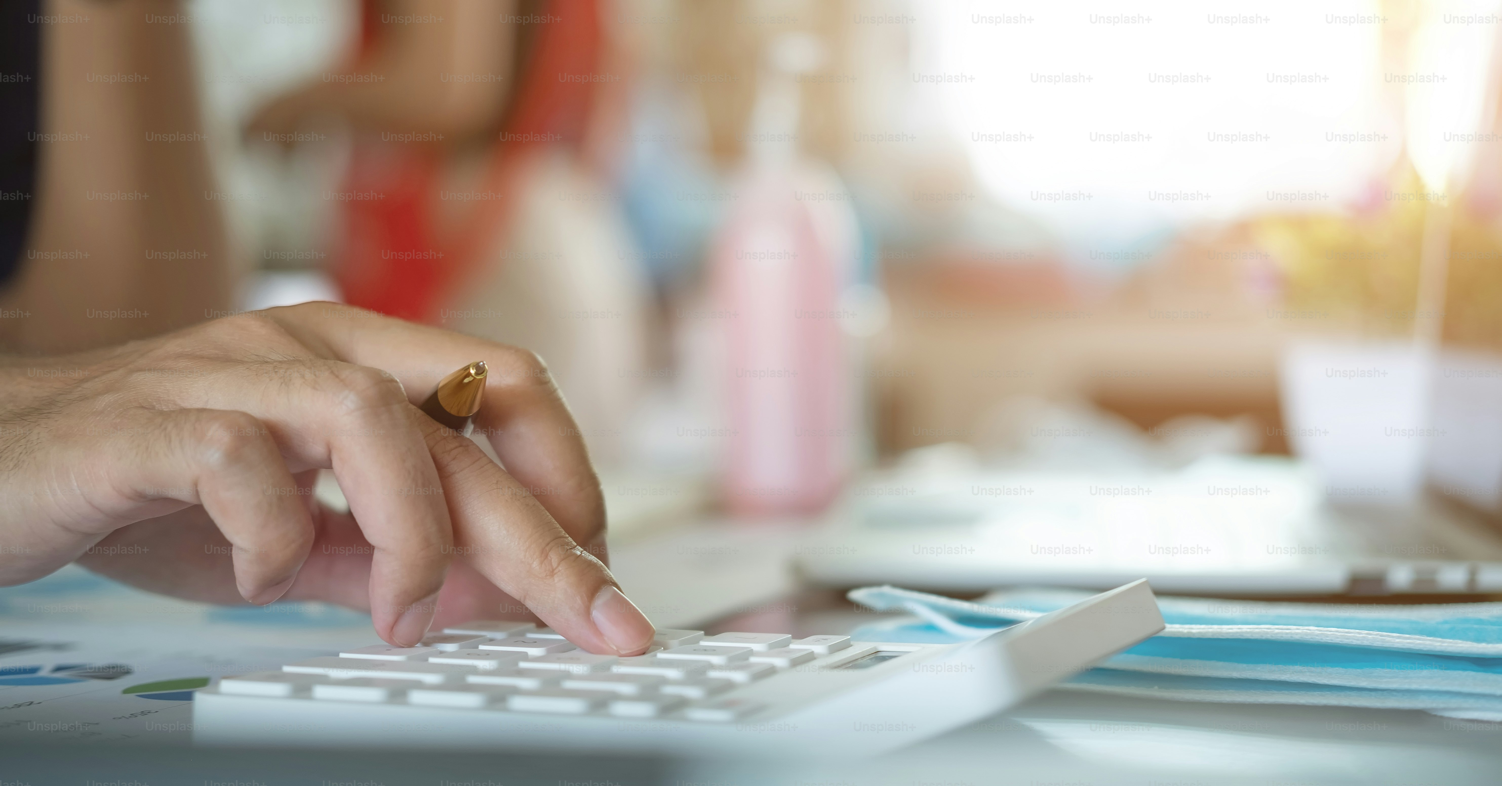 Close up hand of businessman working on calculator at home during Coronavirus or Covid-19 quarantine