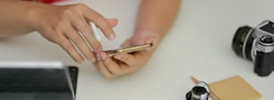 Close up view of photographer working with smartphone on white worktable with photographer supplies