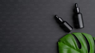 Luxus-Kosmetikflaschen und tropisches Monsterablatt auf schwarzem Hintergrund. Premium-Haarölflaschen Mockup. Natürliches Bio-Beauty-Produkt für Haarpflege- und Behandlungskonzept