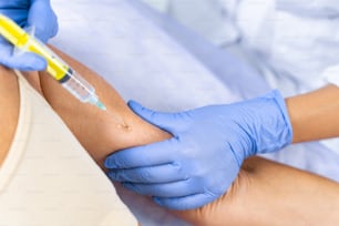 Cropped photo of a doctor in latex gloves giving an injection with a disposable syringe