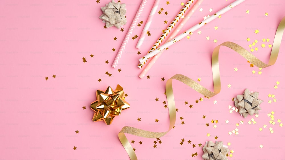 Golden streamers and confetti on pink background. Christmas, birthday or wedding concept. Flat lay, top view.