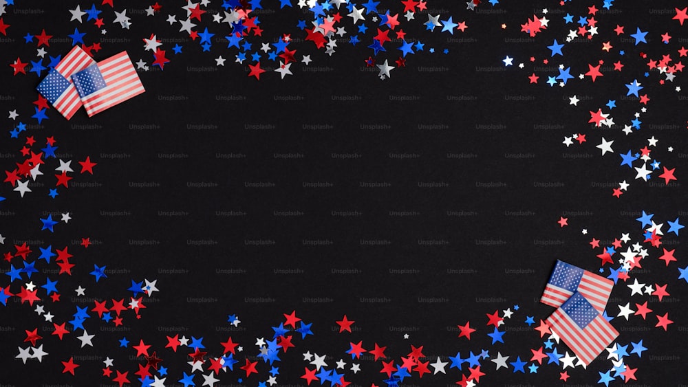 4th of July Independence day celebration background. Frame made of blue, red and white confetti stars and American flags on dark table. US national holidays concept.