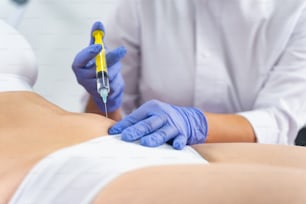 Cropped photo of a female patient in lingerie getting a fat-dissolving injection into the abdomen