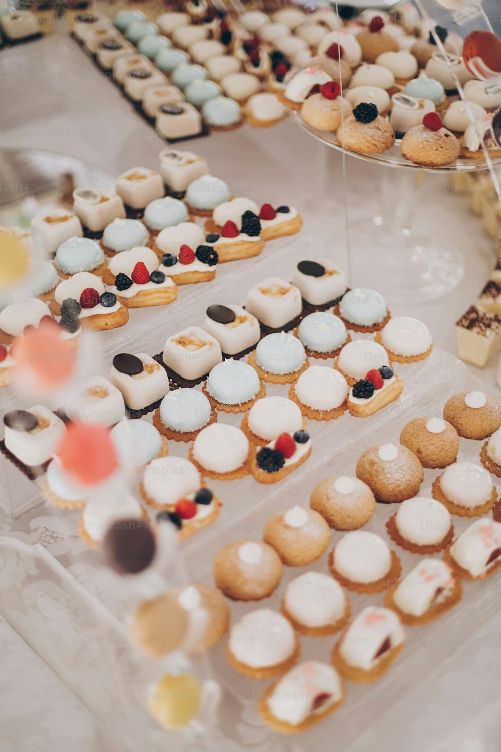 Delicious creamy desserts with fruits, macarons, cakes and cookies on table at wedding reception in restaurant. Luxury catering service. Wedding candy bar.