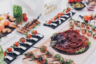 Delicioso aperitivo e canape na mesa na recepção do casamento no restaurante. Serviço de catering de luxo. Delicatessen italiana, lanches de presunto, queijo e azeitonas. Festa de Natal