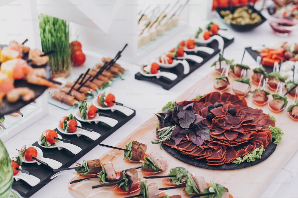 Delicious appetizer and canape on table at wedding reception in restaurant. Luxury catering service. Italian delicatessen, prosciutto snacks, cheese and olives. Christmas feast