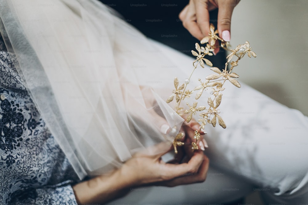 나비와 황금 티아라를 들고 세련된 신부, 결혼식 날을 위한 아침 준비. 현대적인 정통 화환으로 머리를 스타일링하는 미용실의 신부