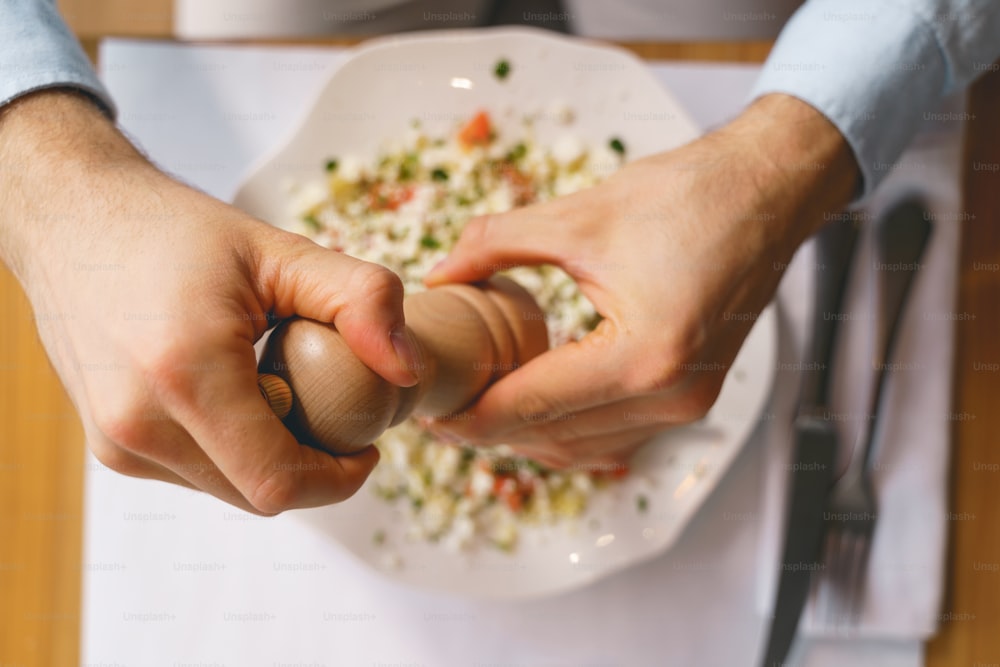 Gros plan de mains masculines ajoutant du sel à une délicieuse salade fraîche