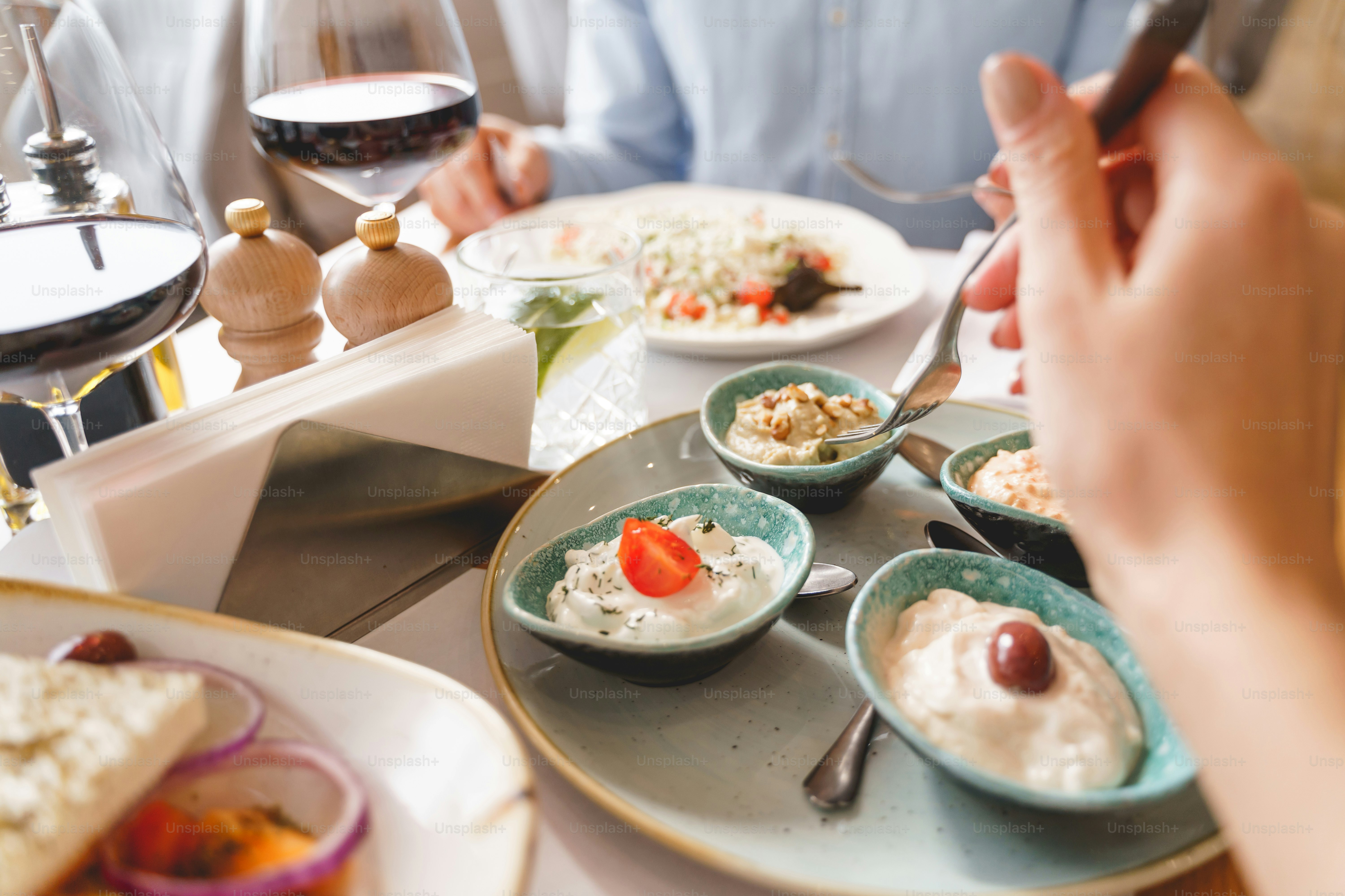 Close up of female hand holding fork while sitting at the table with set of cream food for adding flavor, moisture, and visual appeal to dish
