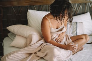 Young sick woman at home. Beautiful woman lying on bed having stomach pain.