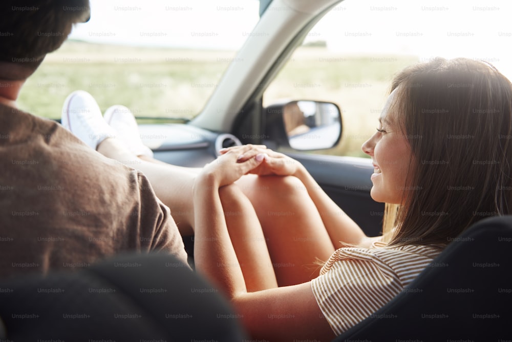 Mujer joven que viaja en automóvil con las piernas en el tablero.