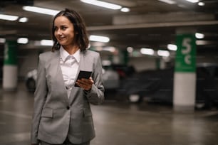 Businesswoman in garage unlocking car and using phone