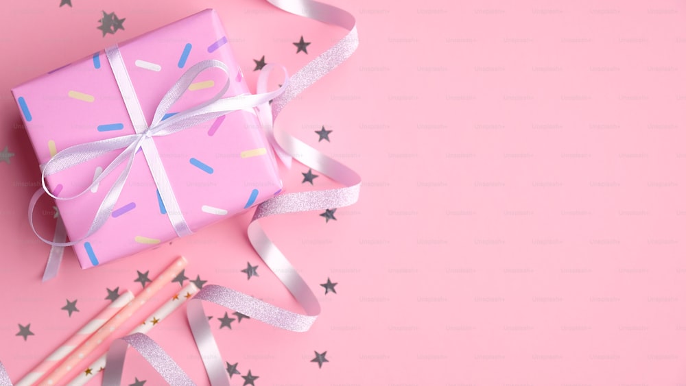 Flache Lay-Komposition mit leuchtend rosa Geschenkbox, Getränkestrohhalmen, Silberband und Konfetti. Erstes Baby Geburtstagsparty Feier Konzept.