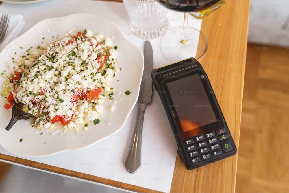 Top view of delicious food, knife and terminal for contactless payment on wooden table