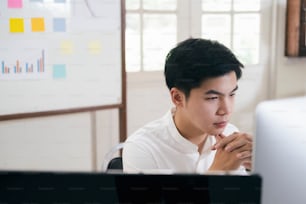 Jeune analyste de marché financier travaillant au bureau et analysant le marketing en ligne dans son ordinateur.