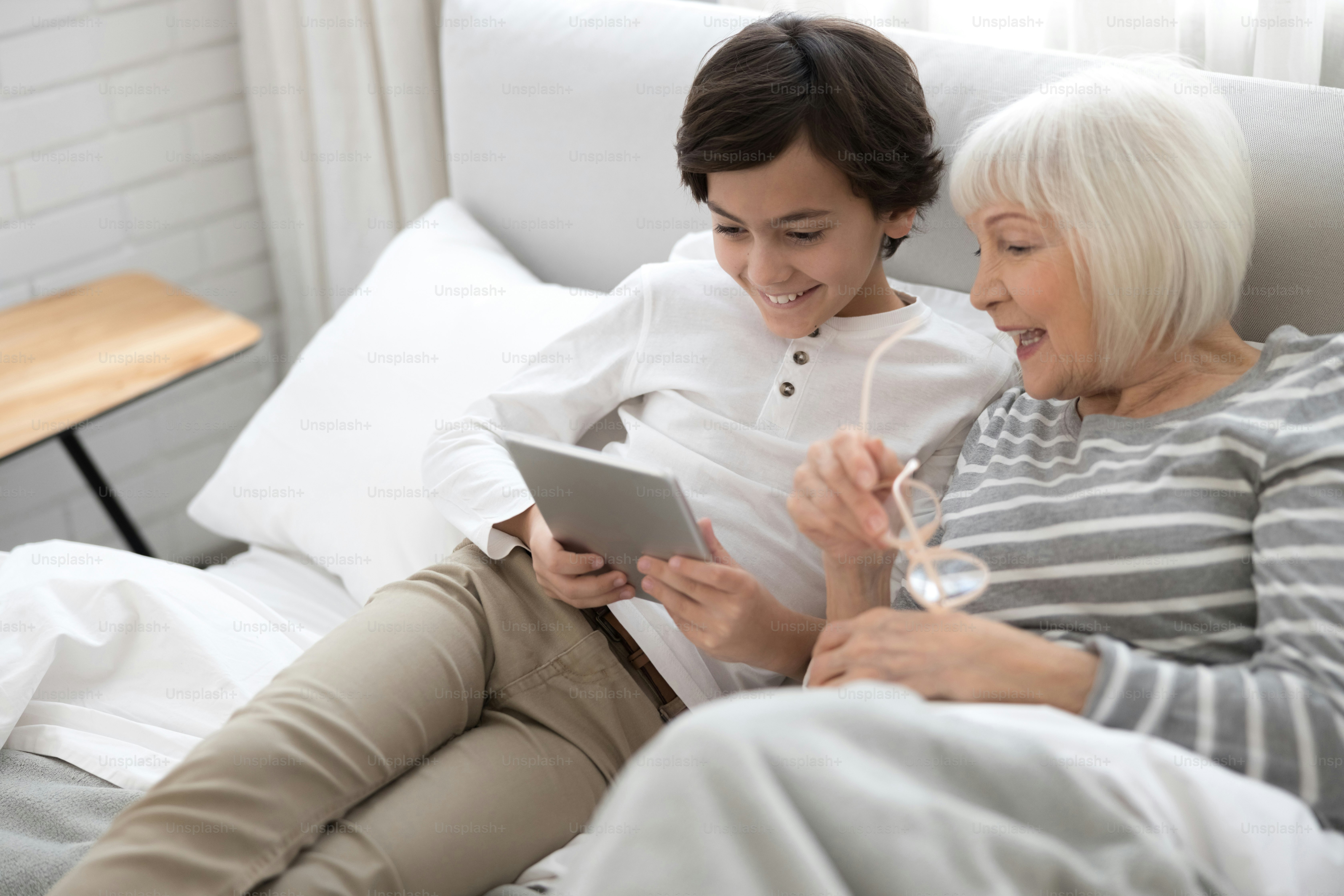 Smiling senior woman and her joyful grandson looking at the screen of the tablet computer