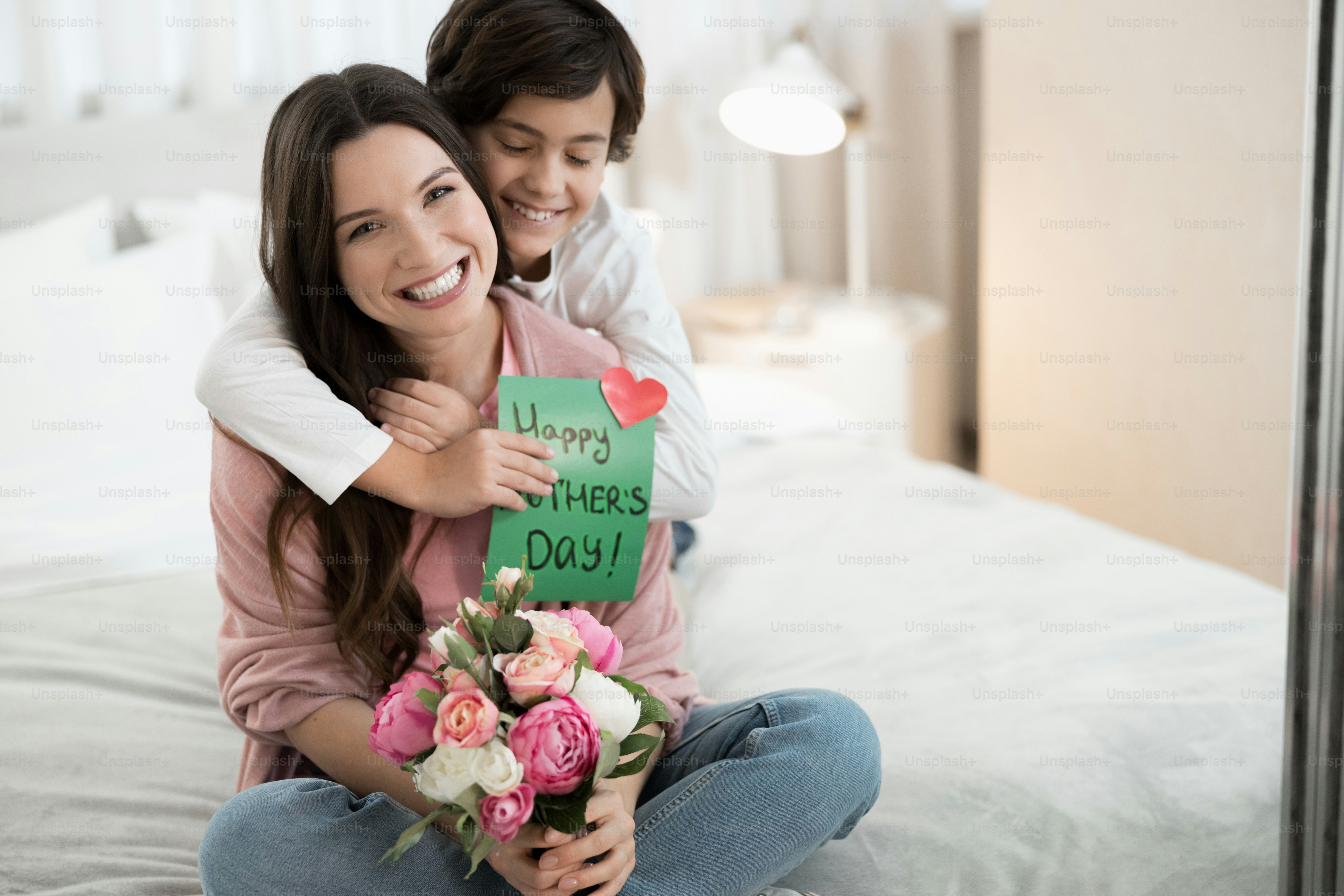 Blissful cute dark-haired Caucasian male child with the eyes closed embracing his mother from behind