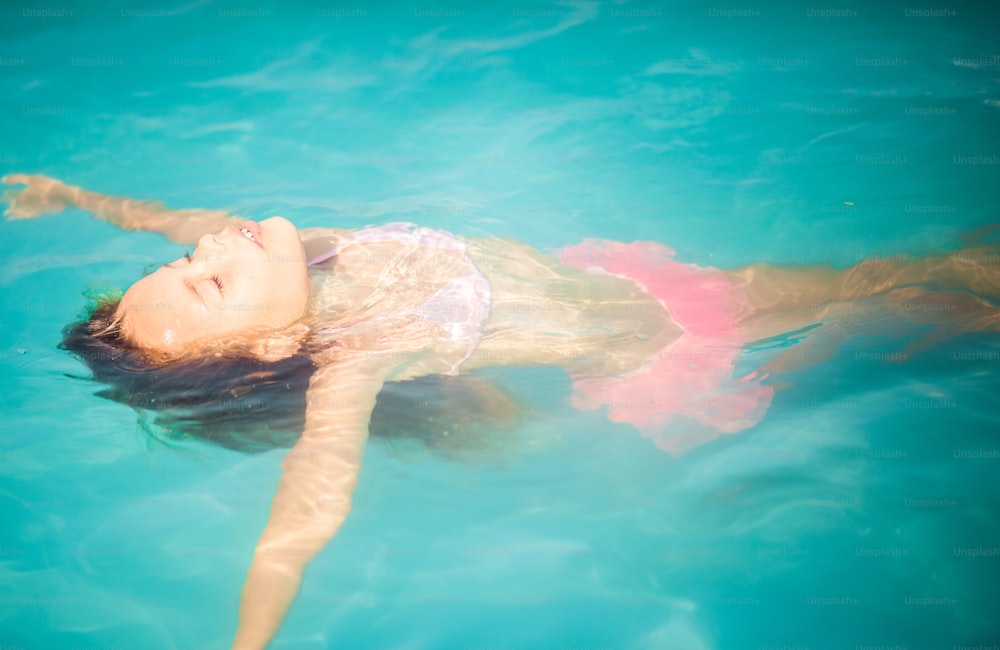 Rilassati e divertiti. Bambina che nuota in piscina.