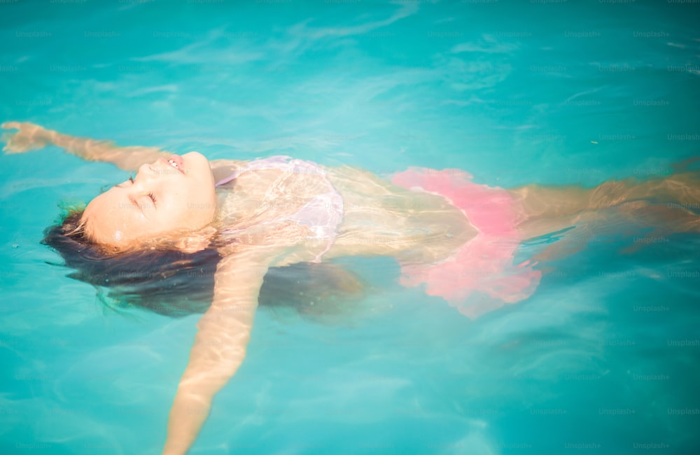 Just relax and enjoy. Little girl swimming in the pool.