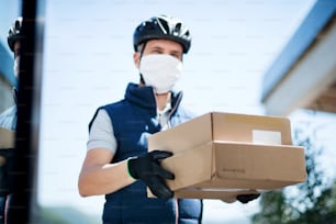 小包、コロナウイルス、検疫コンセプトを配達するフェイスマスク付き宅配便の正面図。