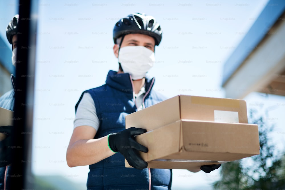 Front view of courier with face mask delivering parcel, corona virus and quarantine concept.