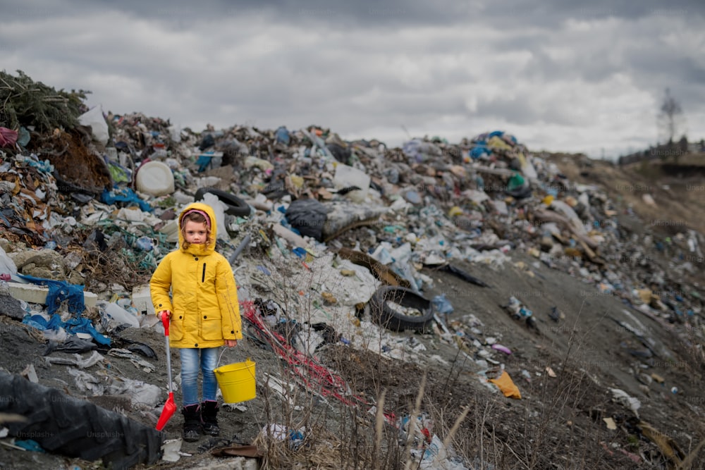 Vue de face d’un petit enfant debout sur une décharge, concept de pollution de l’environnement. Espace de copie.