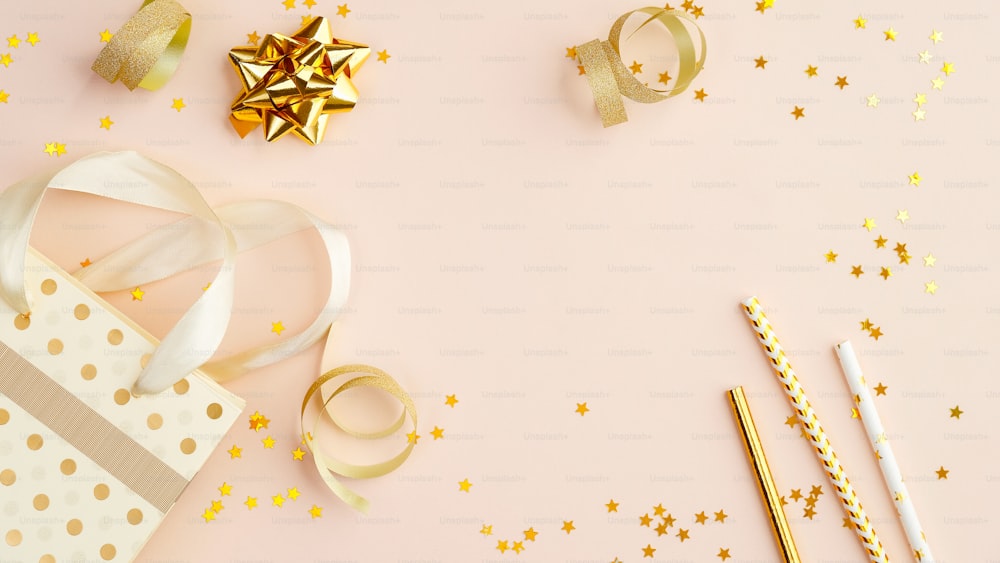金の紙吹雪と装飾、ギフト、ストローを飲むお祝いの背景。誕生日パーティーの招待状のモックアップ。