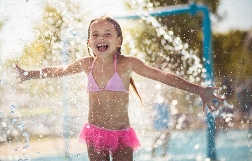 L’été est une saison formidable. Petite fille jouant dans la piscine. Regarder la caméra.